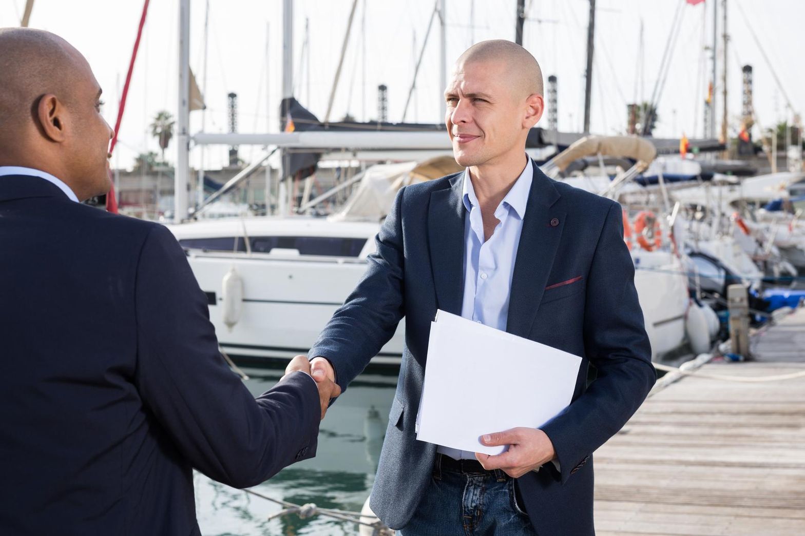 Yacht broker shaking hands with client at marina